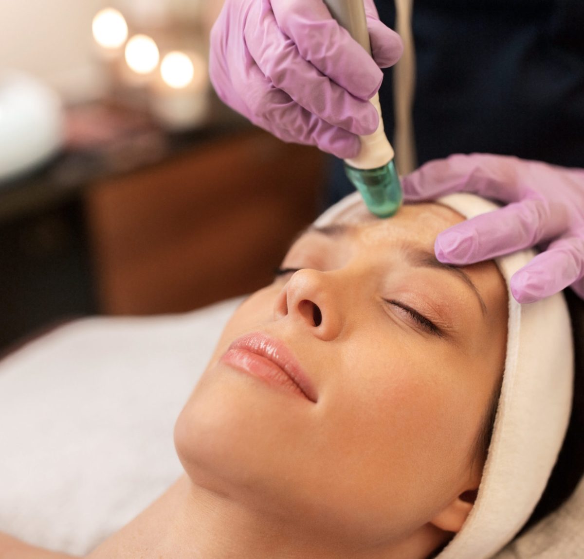 people, beauty, cosmetology, exfoliation and technology concept - beautiful young woman having microdermabrasion facial treatment with crystals in spa